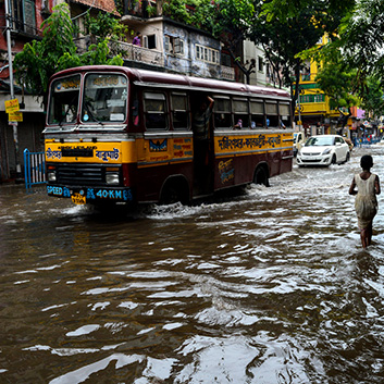 A bus driving through a flooded street in India.