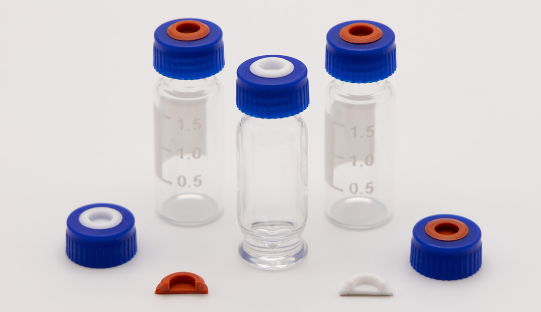Blue screw caps with red and white septa displayed with glass sample vials and molded liner inserts