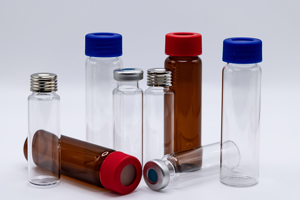 A collection of clear and amber glass laboratory vials with various blue, red, and silver closures