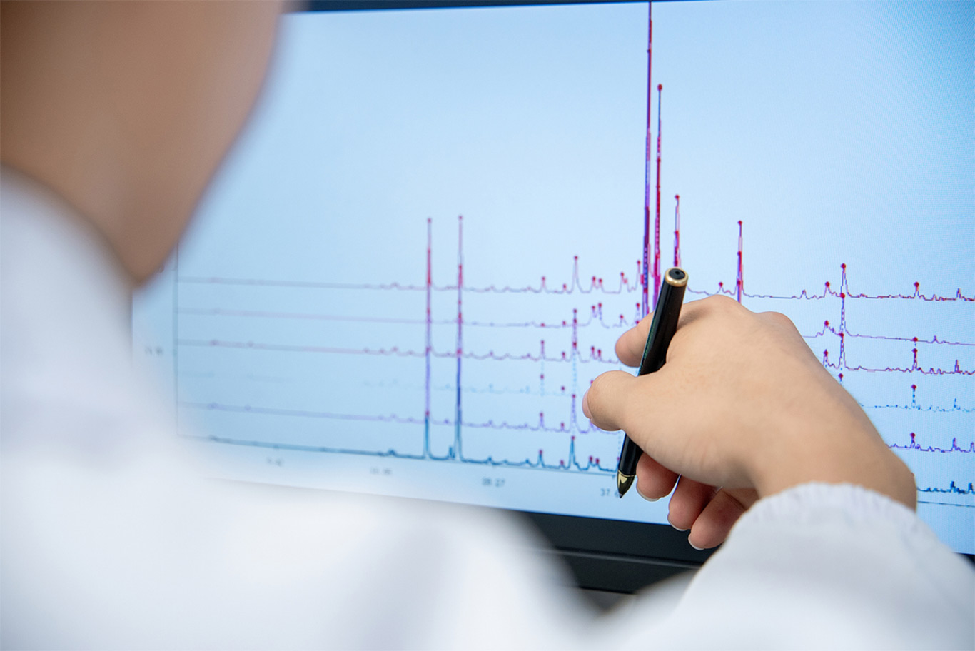 A laboratory technician analyzing a chromatogram with multiple peaks displayed on a computer screen