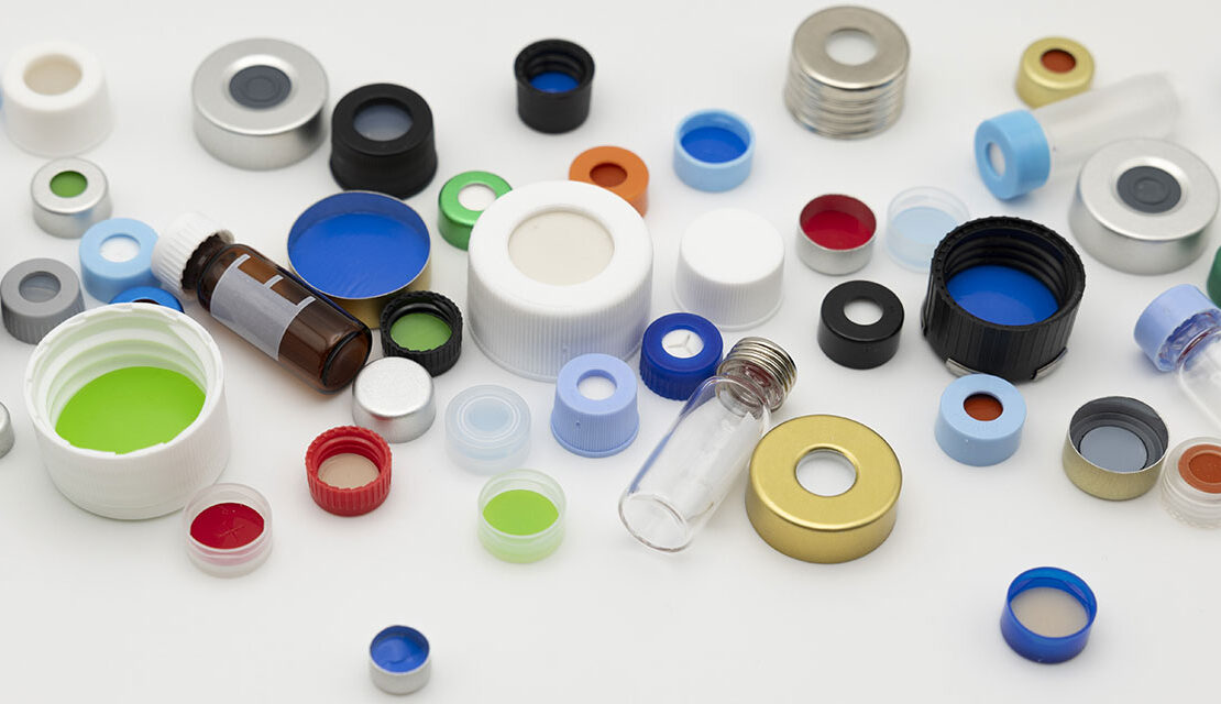 A scattered assortment of colorful laboratory vial caps, septa, and small glass vials